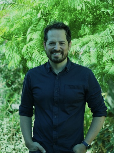 Idan Dorshav Dershowitz standing outdoors among green foliage